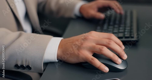Business person hands using computer mouse and keyboard at desk in office setting.