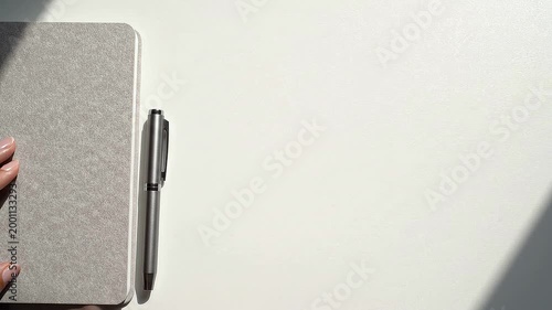 Person Writing with Pen on Notebook in Bright Natural Light Setting