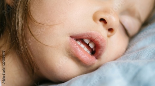 Close-up of a sleeping childs face, mouth slightly open, peaceful slumber.