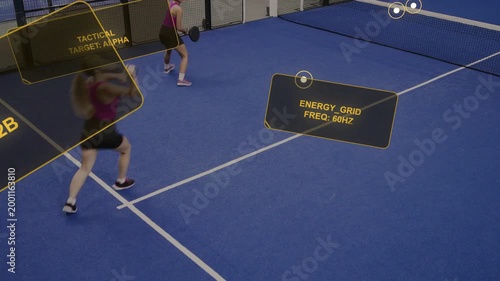 Near-side female player swinging at yellow ball, preparing sports shot while AR labels persisting