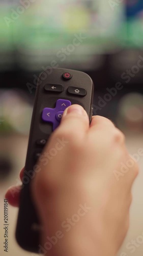Person using a smart tv remote control for navigating the streaming service menu, changing channels and browsing multimedia content, close up of a hand pressing buttons
