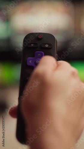 Person browsing channels and streaming services on a smart television using a remote control to navigate the media player interface and watch soccer cup