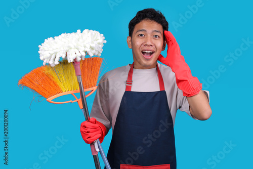 Fotografia Surprised Young Male Cleaner Holding Mop Broom While Touching His Head in Amazem