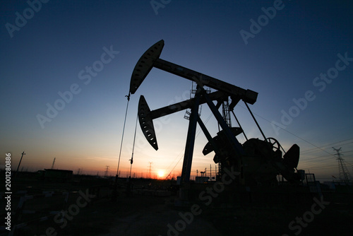 Oil Pump Jack Silhouette at Sunset with High-voltage Towers