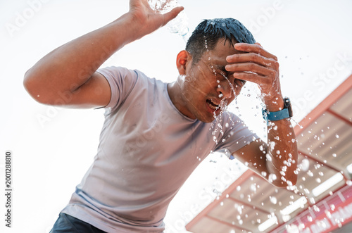 Athlete drenches face with water seeking refreshment after a hot workout in the sun