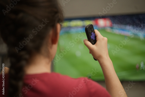 Bild auf Leinwand Young woman relaxing at home, watching an exciting soccer championship match on