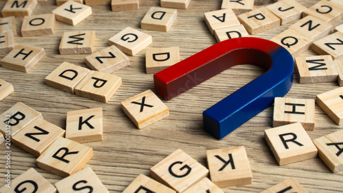 Tableau sur toile Large horseshoe magnet pulling wooden letter tiles on a wooden surface representing customer attraction, marketing leads, and persuasive communication