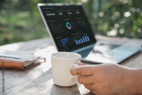 Quadro em tela Business reflection moment with hand holding coffee while viewing laptop analyti