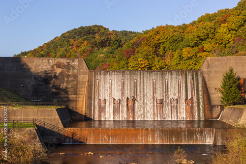 Dam with cascading water in a colorful autumn landscape in Japan.