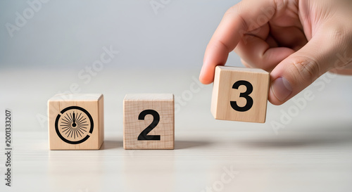A hand places a block with the number 3 on a table with two other blocks.