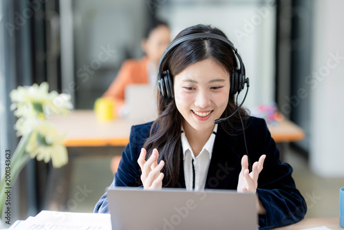 Foto Smiling businesswoman in headset discussing with customer during online video co