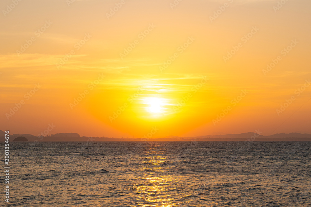 Fototapeta premium nature sky breathtaking golden sunset over a calm ocean, with the entire sky and water bathed in brilliant shades of yellow and orange. Streaky clouds enhance the dramatic display 