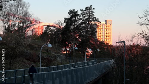 Stockholm, Sweden A man walks on a pedestrian path, Vikdalsvagen, in the Nacka suburb and the Svindersviksbron bridge in the background. 