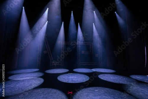 Fényképezés Stage lighting setup with multiple beams illuminating circular spots on the floo