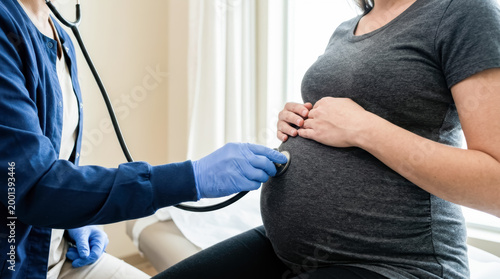 Doctor using stethoscope to examine pregnant woman in clinic, prenatal care concept for maternity health, pregnancy checkup, obstetrics, baby wellness, medical support, and family care.
