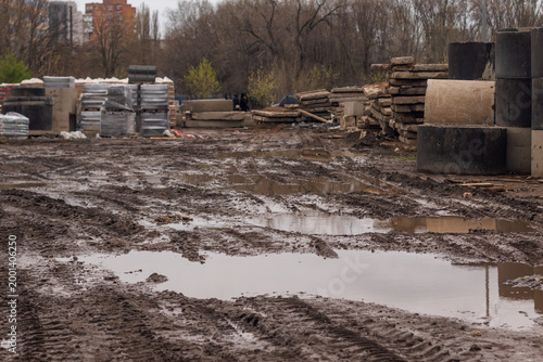 Numerous traces of various equipment at a construction site in the mud and puddles after rain