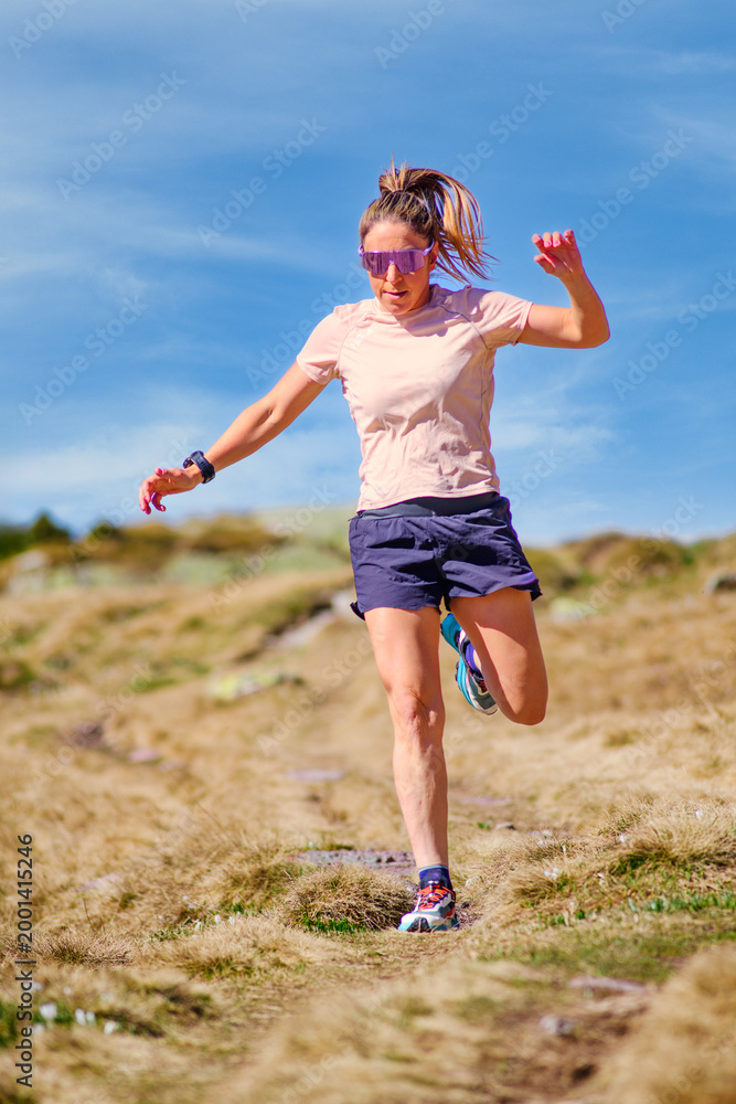 Fototapeta premium Female Trail Runner Jumping on Rocky Path