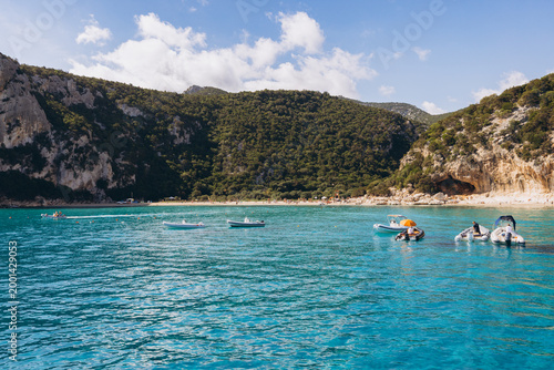 Εκτύπωση καμβά Cala Luna beach with boats anchored offshore, turquoise water, cliffs, and sunba