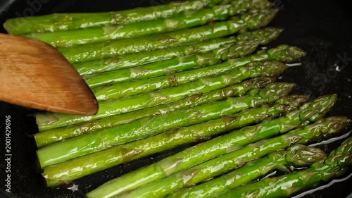 Process frying green asparagus in pan. Healthy vegan food concept