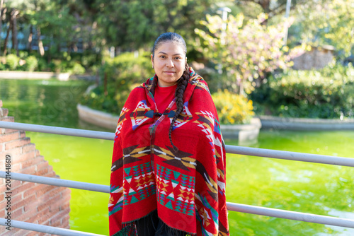 Indigenous Latin woman posing outdoors, representing culture and heritage in her detailed poncho