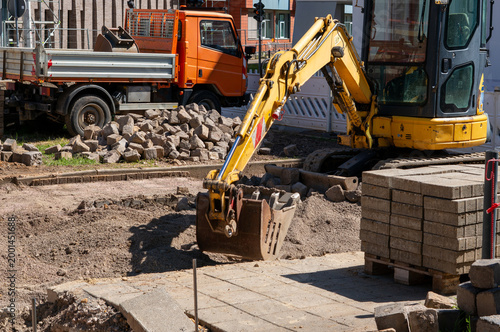 New parking lot construction in the city with an excavator and concrete blocks at a construction site
