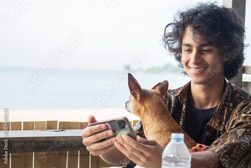 Tableau sur toile Young man taking a selfie with his phone with his adorable dog on his lap on an