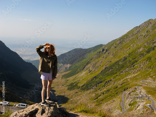 Fotografía Two women stand atop a rock, admiring the stunning landscape of the Transfagarasan mountain route in Romania on a clear day
