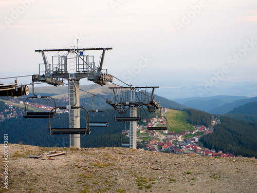 Foto A chairlift carries passengers up a mountain, showcasing beautiful green hills and a quaint village below