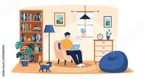 Young man wearing headphones sits comfortably in an armchair working on his laptop at home while his black cat walks across the wooden floor.