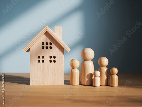A wooden house model with a family of wooden figures standing beside it on a table