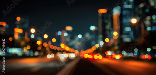 A blurry night view of a city street with bokeh lights and tall buildings