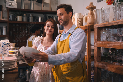 Foto Ceramic shop with couple choosing dishware in cozy interior