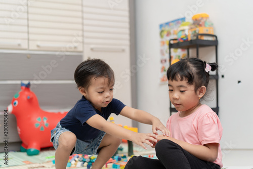 Little boy and girl interacting while playing with toys at home
