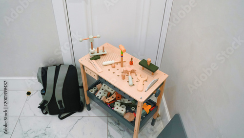Fényképezés Wooden toy workbench with tools and parts in a room with tiled floor