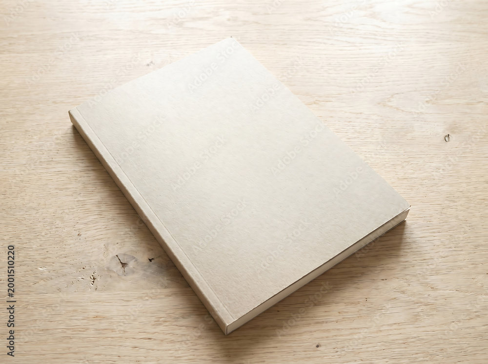 Fototapeta premium A blank book lies closed on a wooden table indoors