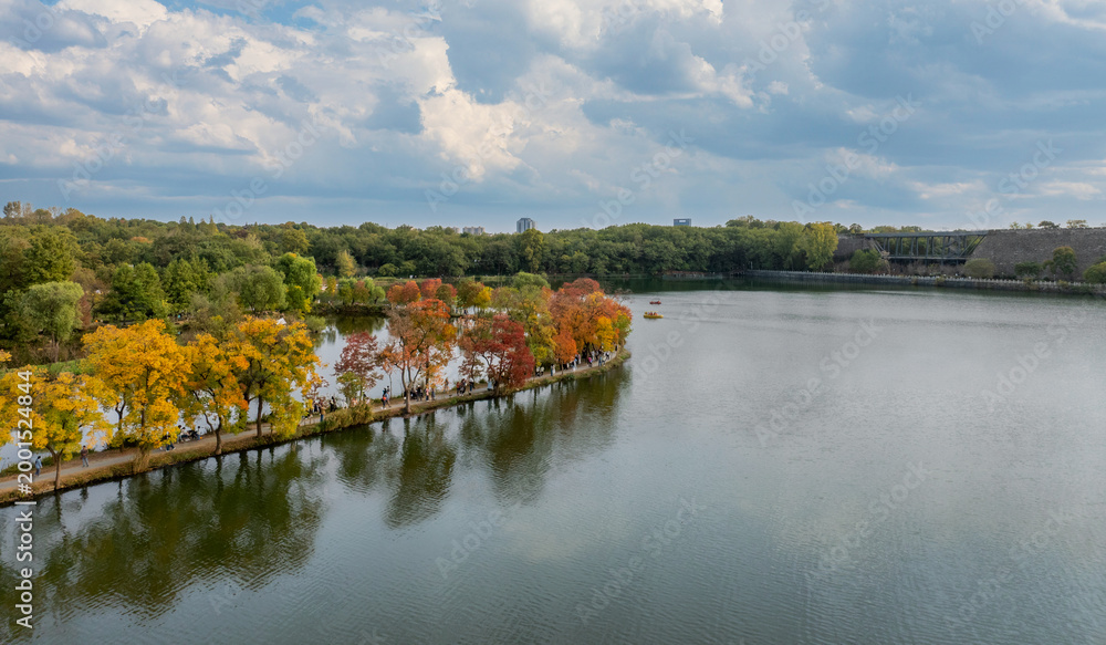 Fototapeta premium Aerial View of Nanjing Botanical Garden's Crescent Dike: Autumn Lakeside and City Skyline