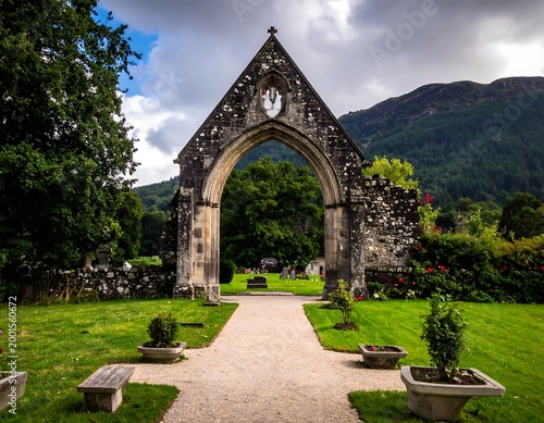 Ruins of an old stone archway overlooking a green landscape with mountains