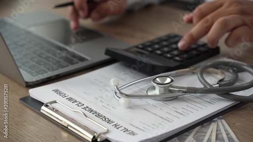 Healthcare cost calculator on health insurance claim form with US dollar bills, stethoscope, and pen on laptop, medical financial planning for hospital expenses and policy coverage budget.