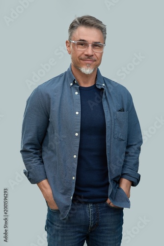 Casual mid adult man standing hands in pocket. Portrait of happy middle aged male in 50s with gray hair and glasses, smiling. Isolated on white background.