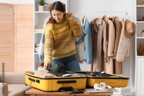 Young woman packing suitcas...