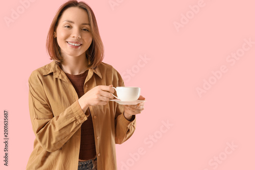 Young woman with cup of tea on pink background