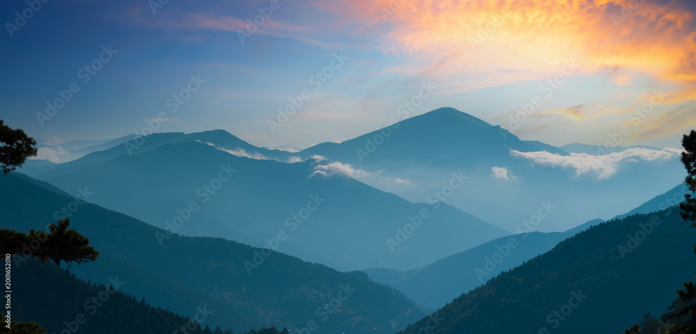 Fototapeta premium Beautiful views of the mountain ranges. Misty peaks and sunset silhouettes.
