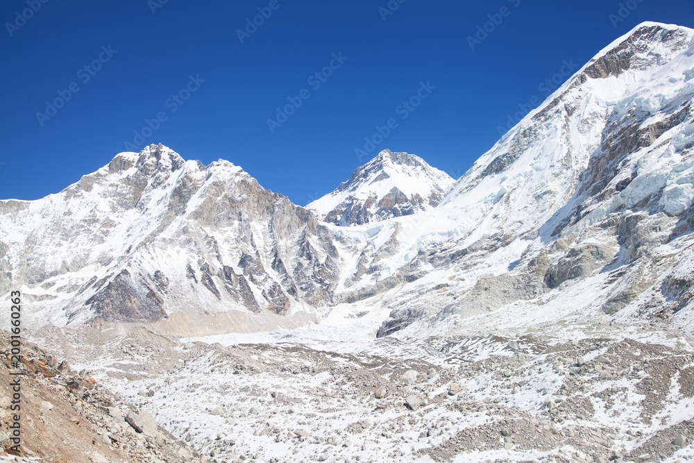 Obraz premium Everest base camp in off-season on the everest base trek, empty of tents and climbers, beneath himalayan peaks under a blue sky.
