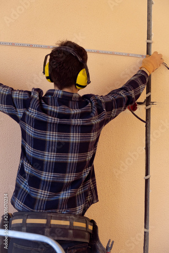 Worker measures in indoor space before starting electrical installation and construction work preparation stage