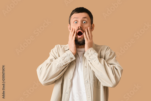 Photos Shocked young man on beige background