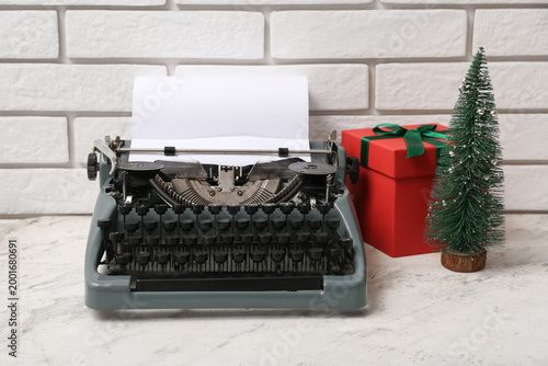 Vintage typewriter with Christmas tree and gift box on white table