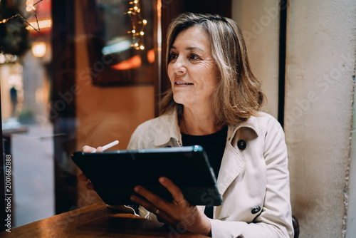 Photos Successful woman using stylus pen with digital tablet in street cafe