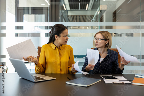 Foto Two stressed businesswomen at a modern office table, one gesturing emotionally w