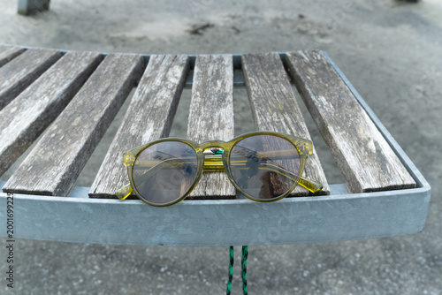 High angle view of yellow transparent sunglasses on a weathered wooden park bench