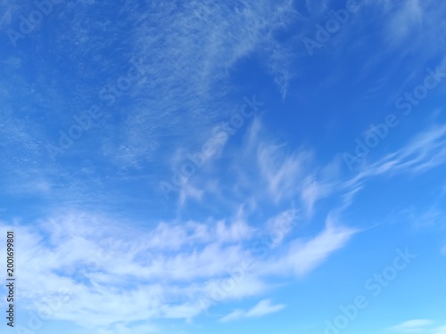 Bright blue sky with delicate wispy cirrus clouds. Clear sunny day weather background. Copy space for text